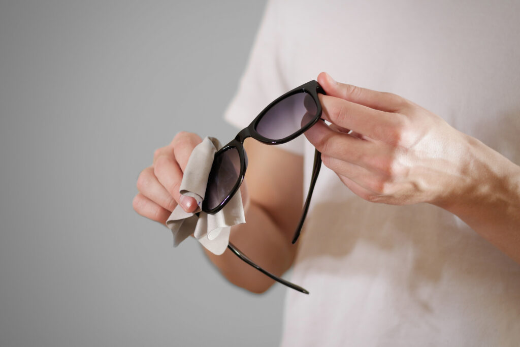 Ragazzo intento a pulire gli occhiali da sole con un pannetto